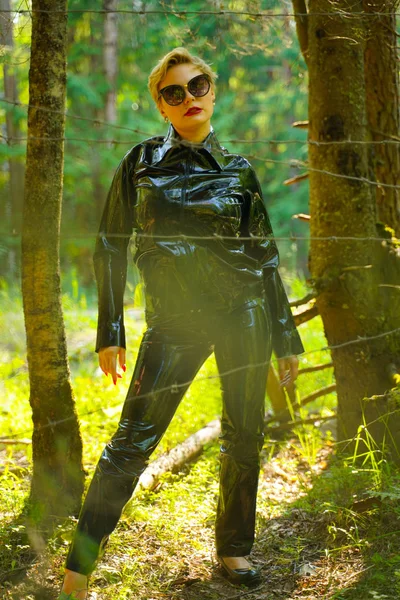 Латексная резиновая мода женщина, гуляющая по лесу — стоковое фото