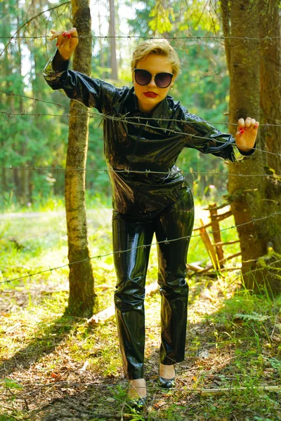 Latex gummi mode kvinna går i skogen — Stockfoto