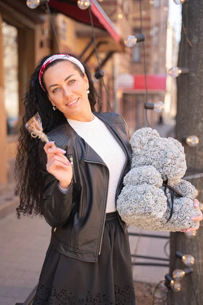 Mujer bonita caminando por la ciudad con oso de peluche gris de rosas espumosas . — Foto de Stock