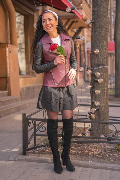 Joven hermosa chica bonita con el pelo largo con rosa roja en la ciudad — Foto de Stock
