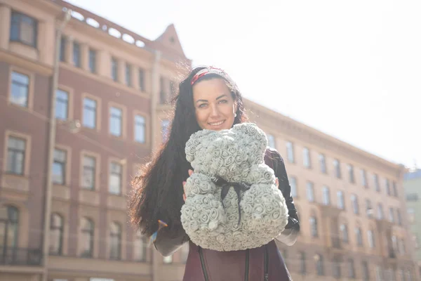 Mujer bonita caminando por la ciudad con oso de peluche gris de rosas espumosas . — Foto de Stock