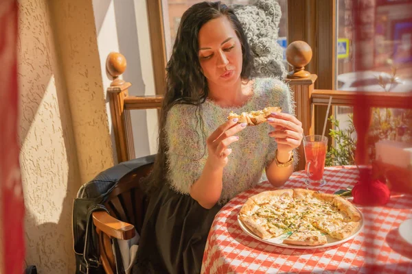 Смешная брюнетка в свитере ест пиццу в ресторане . — стоковое фото