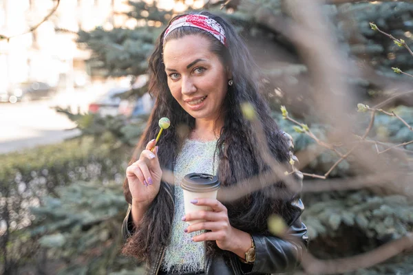 Feliz y linda chica adulta caminando con piruleta y café — Foto de Stock