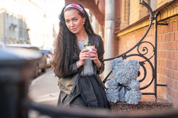 Ganska glada lycklig vuxen tjej med grå nallebjörn från rosor i staden — Stockfoto