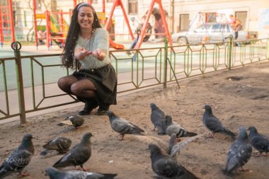Şehir parkında güvercin besleyen genç kadın