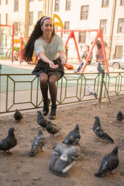 Şehir parkında güvercin besleyen genç kadın