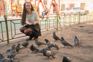 Şehir parkında güvercin besleyen genç kadın