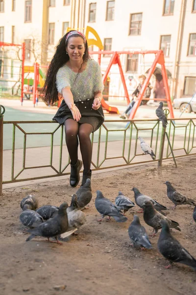 Şehir parkında güvercin besleyen genç kadın