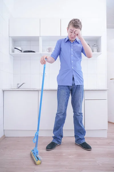 Adolescente menino Mopping o chão e ajuda seus pais a limpar na cozinha — Fotografia de Stock