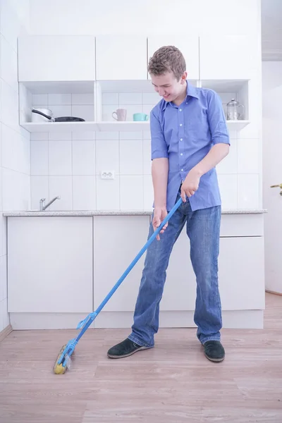 Tonårspojke Mopping golvet och hjälper sina föräldrar att rengöra på kök — Stockfoto