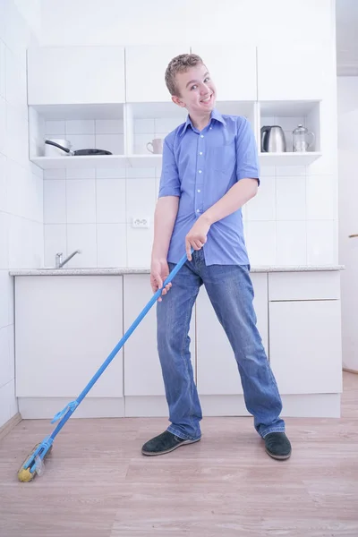 Adolescente Boy Mopping El Piso y ayuda a sus padres a limpiar en la cocina —  Fotos de Stock