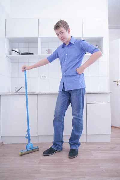 Tonårspojke Mopping golvet och hjälper sina föräldrar att rengöra på kök — Stockfoto