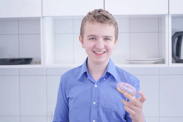 Kleine gelukkige schattige jongen eet donut op witte keuken achtergrond alleen — Stockfoto