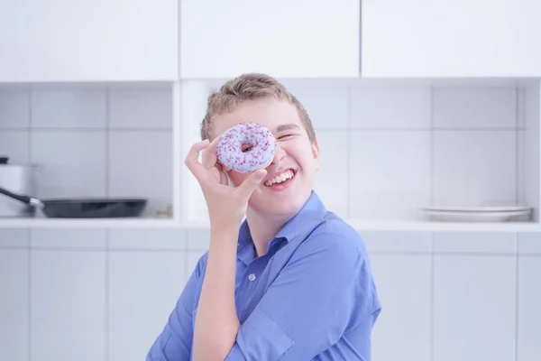 Μικρό χαρούμενο χαριτωμένο αγόρι τρώει ντόνατ σε λευκό φόντο κουζίνα μόνο — Φωτογραφία Αρχείου