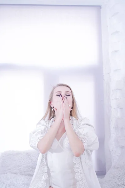 Retrato de una mujer cansada y somnolienta en un alféizar blanco en casa sola —  Fotos de Stock