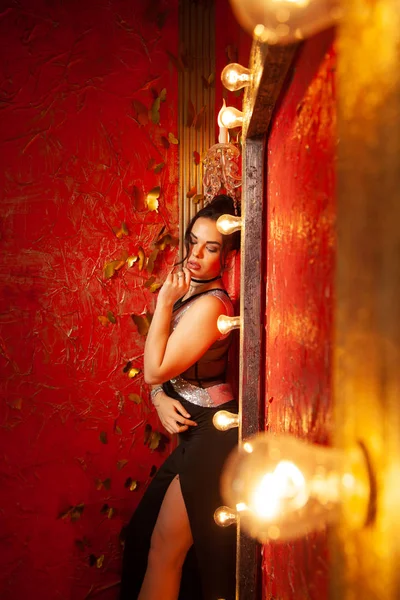 Ampuller ile kırmızı moda odasında parti elbisesi giyen neşeli genç kadın