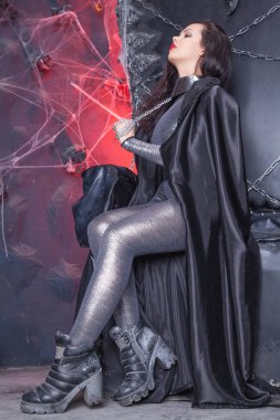 Fütüristik Gotik Kız Siyah Taht Sandalyeüzerinde gümüş parlak catsuit