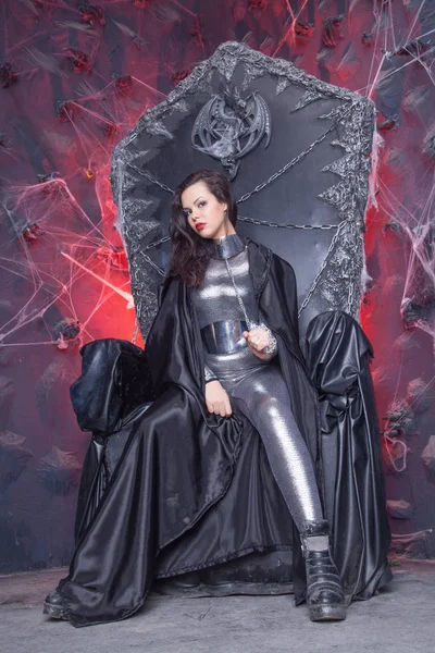 Futuristica Ragazza Gotica in catsuit argentato lucido su Black Throne Chair — Foto Stock