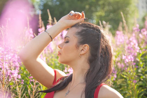 Pretty mixrace brunett tjej i röd klänning poserar i rosa natur blommor fält — Stockfoto