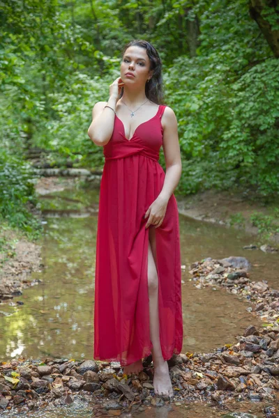 Belle fille dans une robe rouge chic posant dans la forêt de fées . — Photo