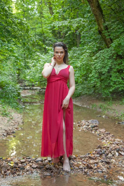 Belle fille dans une robe rouge chic posant dans la forêt de fées . — Photo