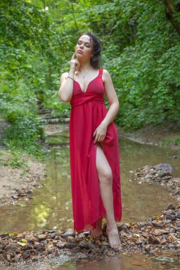Peri ormanında poz veren şık kırmızı elbiseli güzel kız.