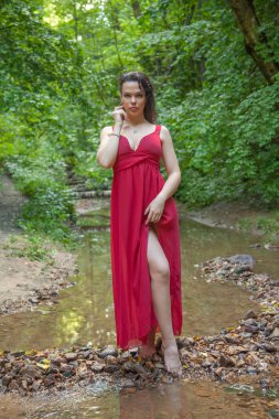 Peri ormanında poz veren şık kırmızı elbiseli güzel kız.