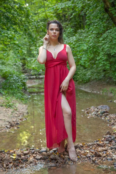 Bella ragazza in un abito rosso chic in posa nella foresta fatata . — Foto Stock