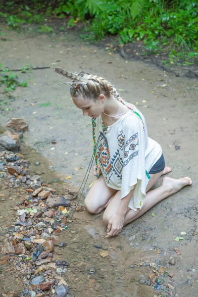 Menina bonita com penas indianas americanas mantém arco e flecha — Fotografia de Stock