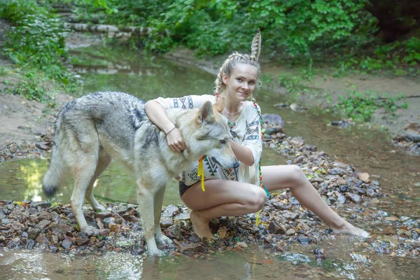 Slank etnisch meisje met haar wolf hond in het diepe bos alleen — Stockfoto