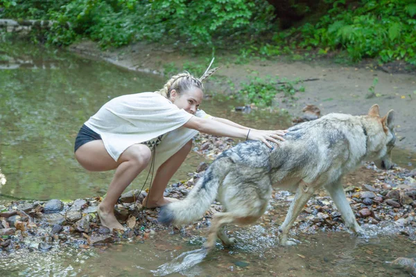 Slank etnisch meisje met haar wolf hond in het diepe bos alleen — Stockfoto