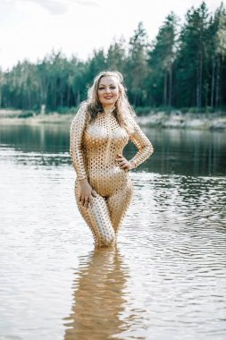 Altın fütüristik kıyafet içinde artı boyutu kıvrımlı vücut ile Kadın suda poz