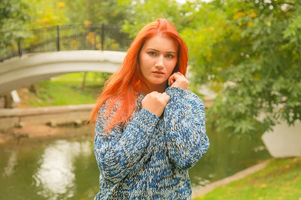 Schöne junge rothaarige Frau im Pullover geht im Herbst spazieren — Stockfoto