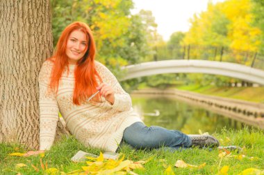 Kazak güzel genç kızıl saçlı kadın sonbaharda yürüyor