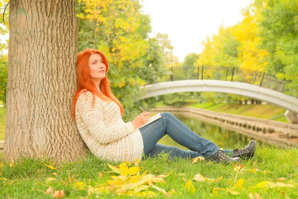 Bela menina ruiva livro de leitura na cidade outono verde e amarelo parque da cidade — Fotografia de Stock