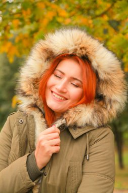 Sarı yeşil ağaçları ile sonbahar parkında kürk kapüşonlu ceket redheaded kadın