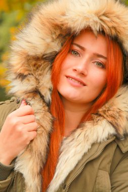 Sarı yeşil ağaçları ile sonbahar parkında kürk kapüşonlu ceket redheaded kadın