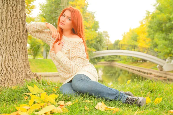 Красивая молодая рыжая женщина в свитере ходит осенью — стоковое фото