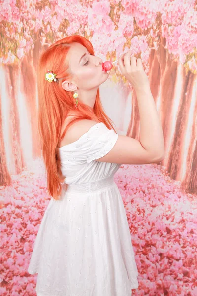 Menina sexy surpreso comer pirulito. Glamour beleza Mulher modelo com cabelo laranja segurando doces rosa — Fotografia de Stock