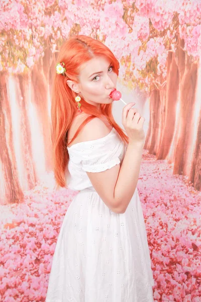 惊讶的性感女孩吃棒棒糖。美女 魅力模特 女人 与 橙色 头发 拿着 粉红色 糖果 — 图库照片