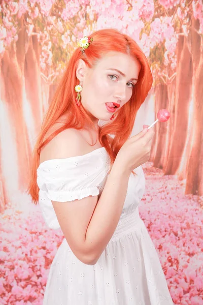 Menina sexy surpreso comer pirulito. Glamour beleza Mulher modelo com cabelo laranja segurando doces rosa — Fotografia de Stock