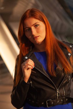 Gün batımında yaz lık şehirde yürüyen şık kızıl saçlı kadın