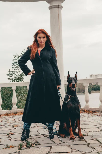 Hermosa mujer propietaria con su perro negro doberman al aire libre caminando juntos —  Fotos de Stock