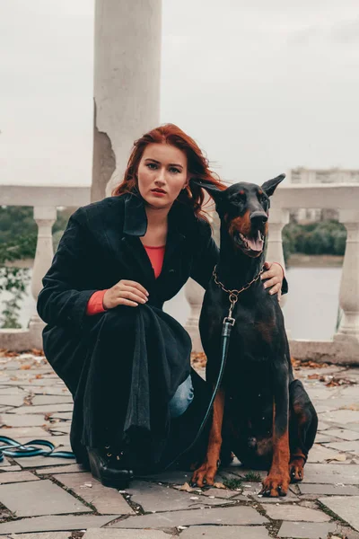 Mooie vrouw eigenaar met haar hond zwarte Doberman buiten wandelen samen — Stockfoto