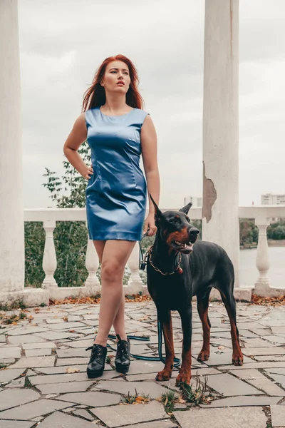 Krásná žena s jejím psem černým dobrmanem venkovní procházky — Stock fotografie