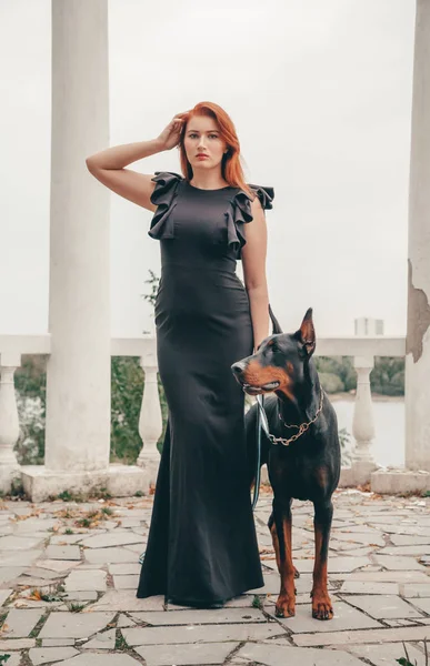 Hermosa mujer propietaria con su perro negro doberman al aire libre caminando juntos —  Fotos de Stock