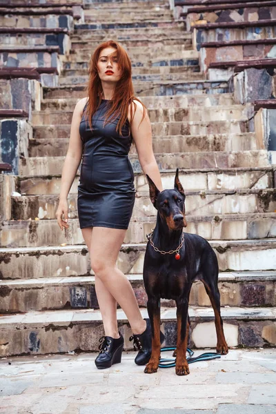 Femeie frumoasă proprietar cu ei câine negru doberman în aer liber de mers pe jos împreună — Fotografie, imagine de stoc