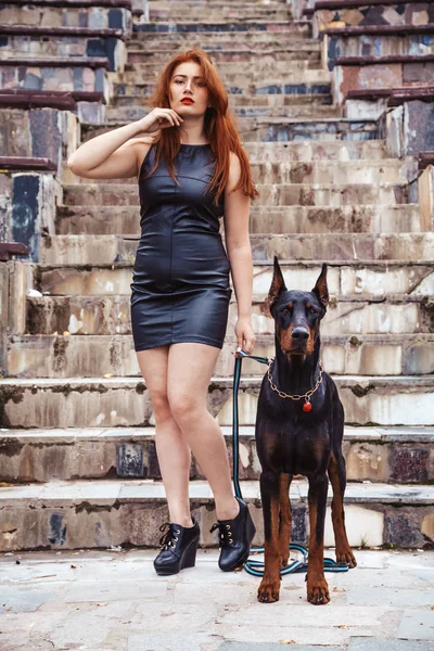 Mooie vrouw eigenaar met haar hond zwarte Doberman buiten wandelen samen — Stockfoto