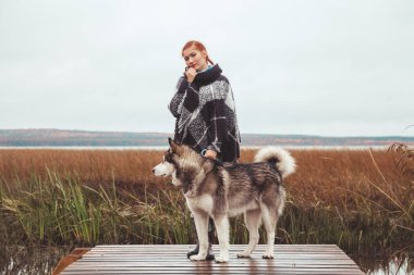 göl yakınında onu malamute gri büyük köpek ile kızıl saçlı kafkas kadın sahibi