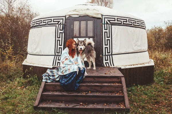 Mädchen mit ihrem Hund malamute in der Nähe ihrer Heimat weit weg von der Zivilisation im Wald — Stockfoto